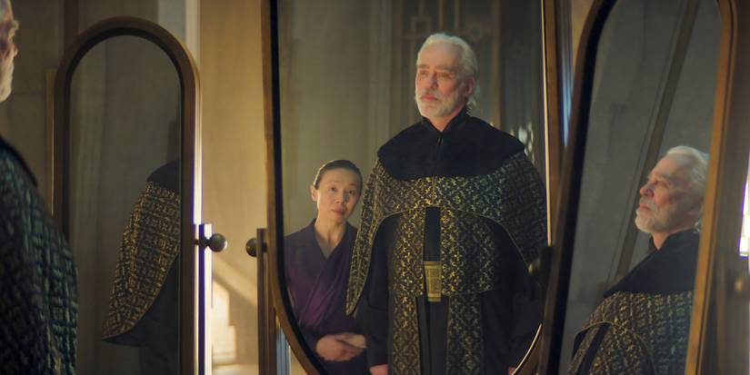 Dusk wearing ceremonial robes and staring at his reflection in three mirrors in the Foundation Season 3 finale