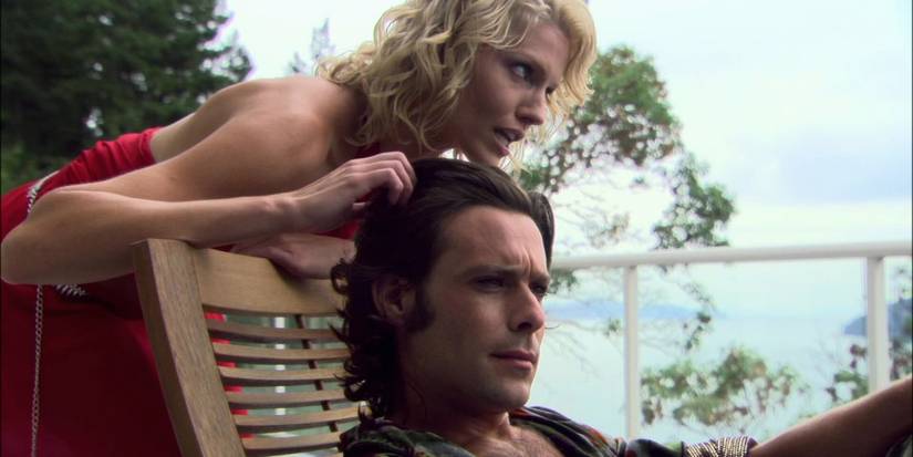 Six playfullly scratches Gaius Baltar's head as he relaxes in a poolside chair in one of Gaius' visions in Battlestar Galactica
