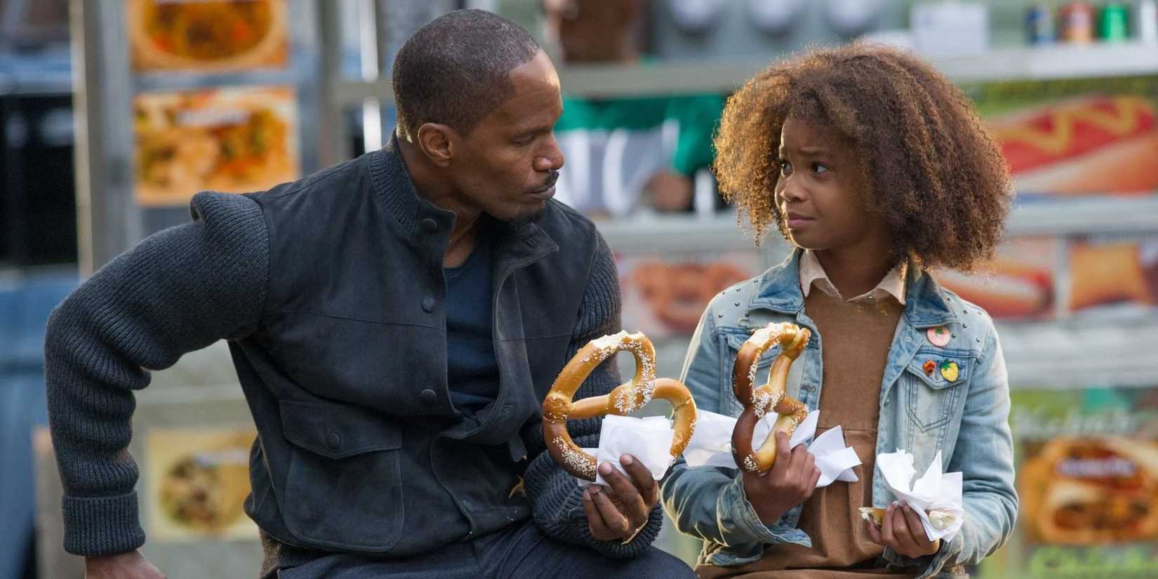 Jamie Foxx as Will Stacks and Quvenzhané Wallis as Annie eat pretzels and look at each other in Annie.