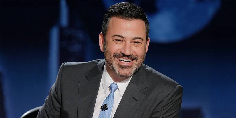 Džimijs Kimmels smaidot aiz sava galda uz Džimija Kimmela Live!