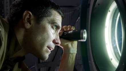 Jake Gyllenhaal shines a flashlight out a portal window in Life.