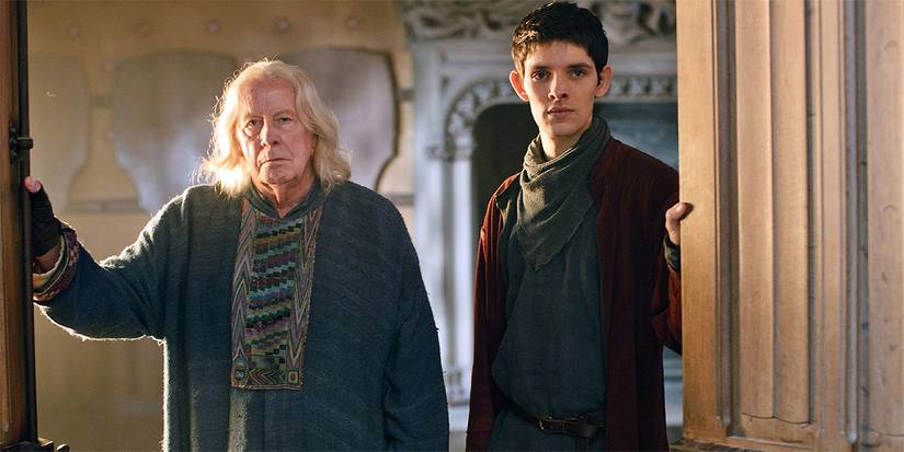 Gaius (Richard Wilson) and Merlin (Colin Morgan) standing at a door together in Merlin.