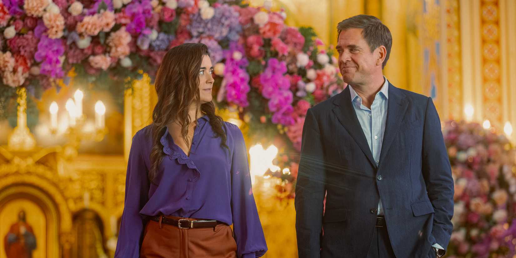Cote de Pablo as Ziva standing next to Michael Weatherly as Tony in front of a flower arch in NCIS: Tony & Ziva