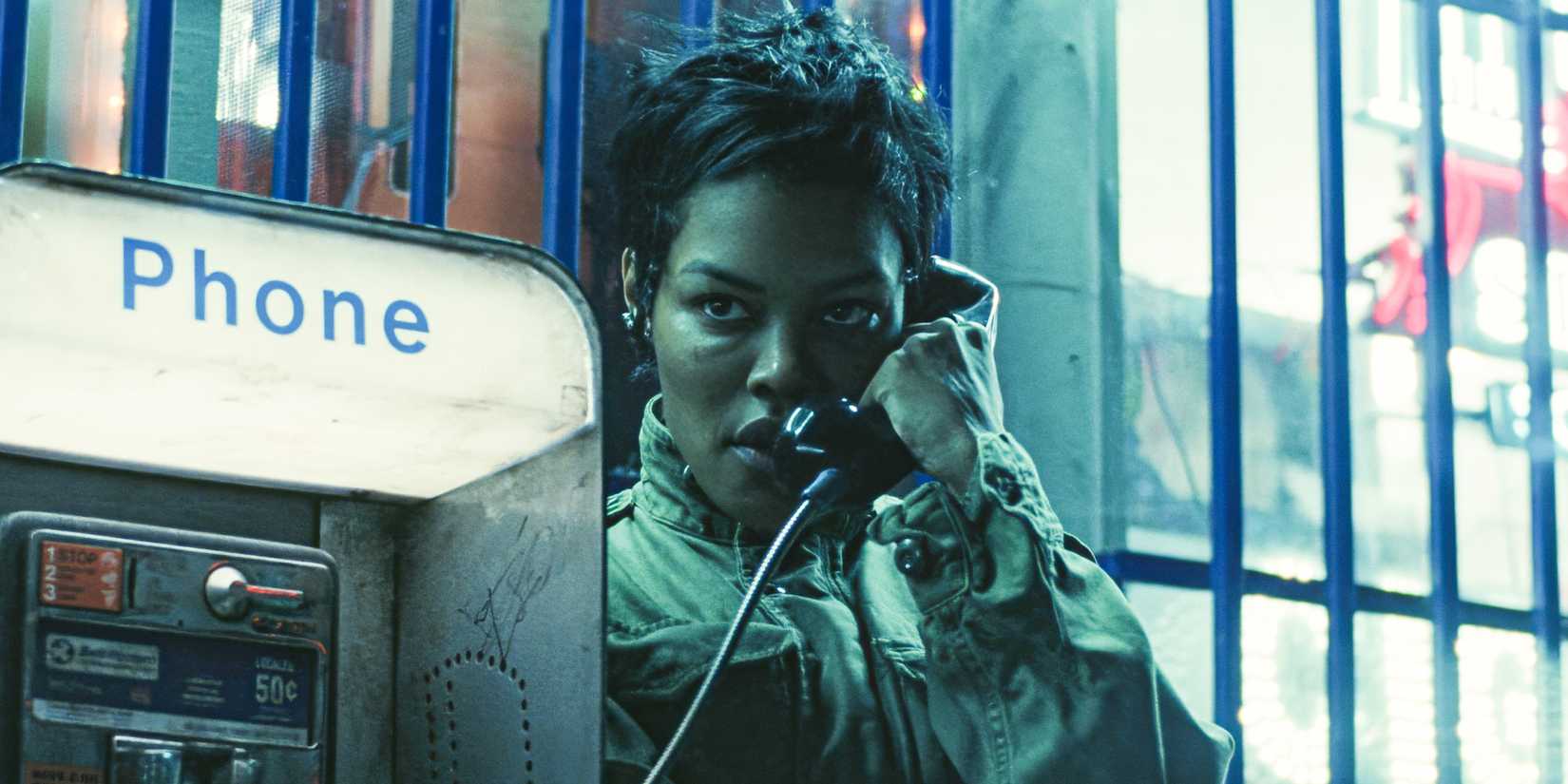 Teyana Taylor on a payphone at night in One Battle After Another 