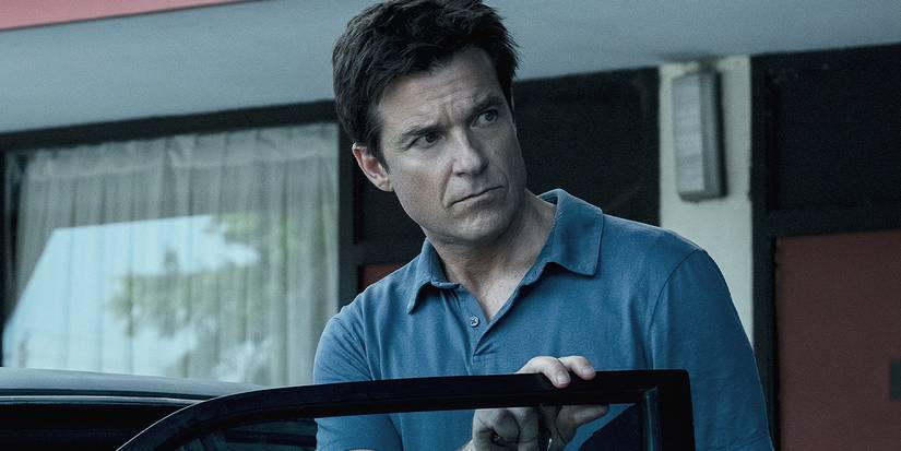 Jason Bateman looking to the side, about to get into a car in Ozark.