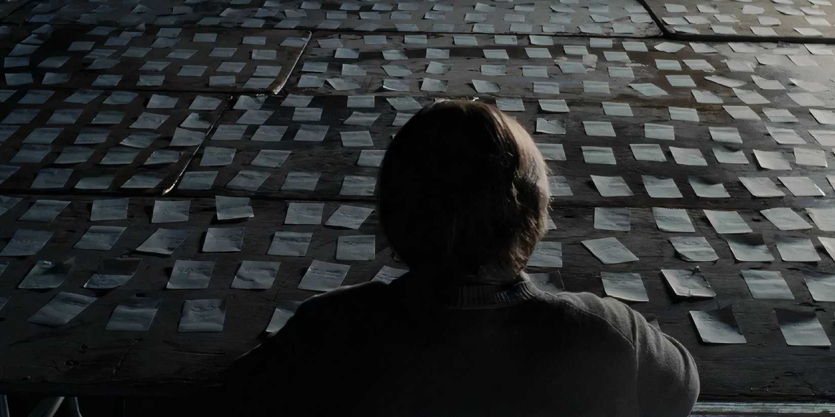 A back shot of Philip Seymour Hoffman as Caden looking at several papers in front of him in Synecdoche, New York