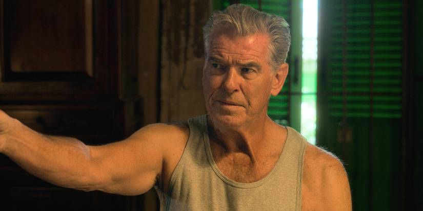Pierce Brosnan em uma camisa sem mangas parecendo perplexa em Fast Charlie.
