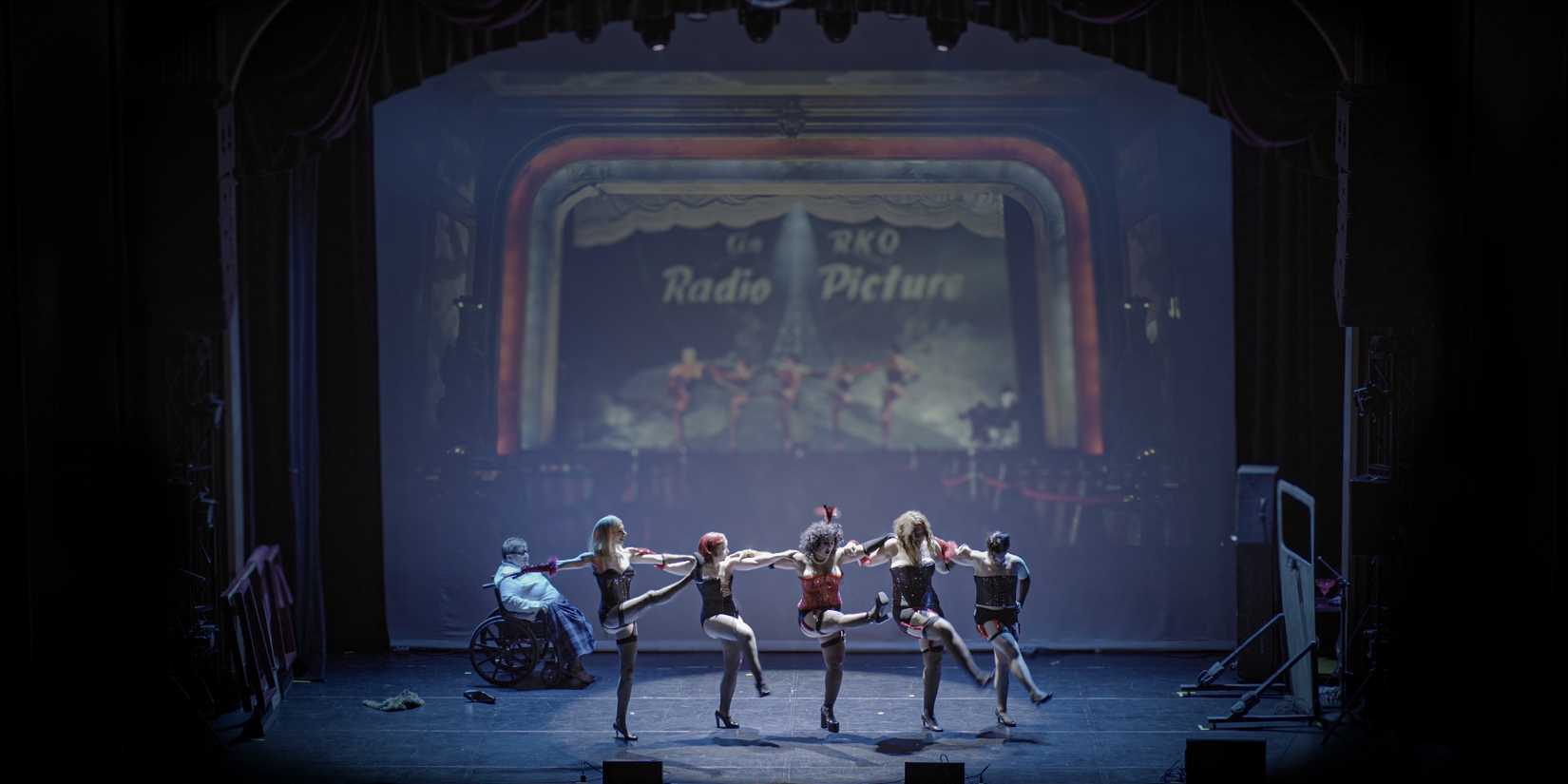 A shadow cast performs The Rocky Horror Picture Show in front of a screen playing the film in Sane Inside Insanity.