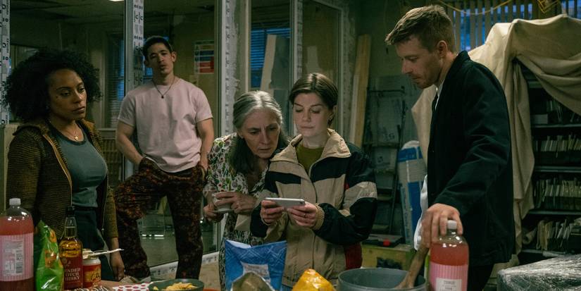 The cast of Slow Horses looking at someone's cell phone in Season 5, Episode 1.