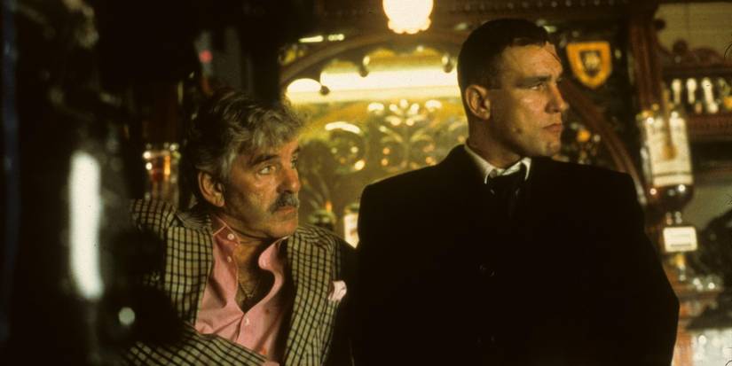 Dennis Farina & Vinnie Jones lean against a bar and look to the right, in Snatch