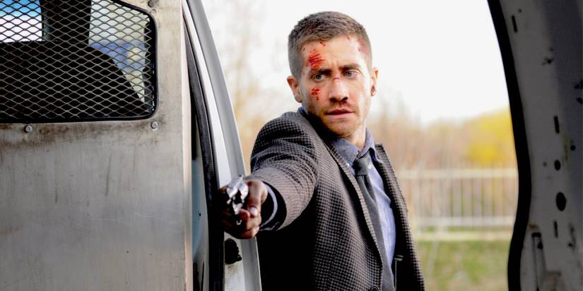 Jake Gyllenhaal, with wounds on his face, aims a gun into a train in Source Code