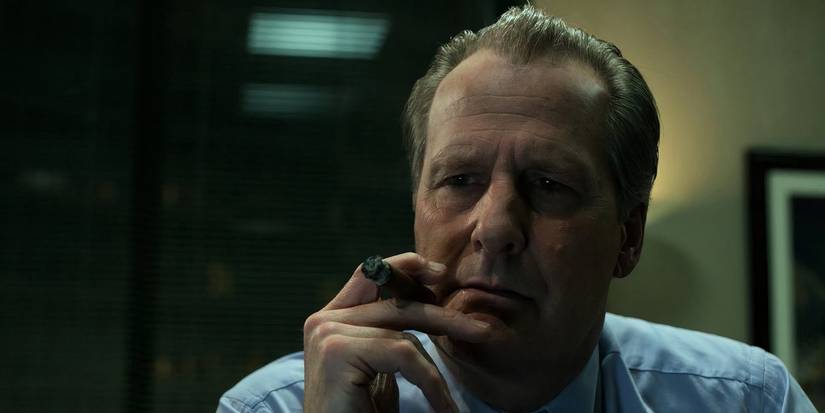 Jeff Daniels looking pensive while smoking a cigar in The Looming Tower