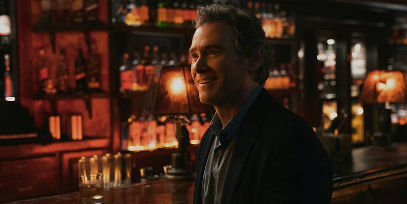 Cory sitting in a bar smiling in The Morning Show.