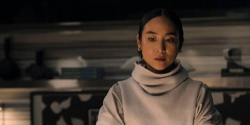 Stella sitting alone in the dark in a white turtleneck in The Morning Show.