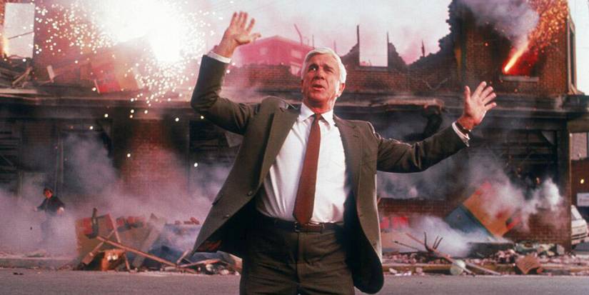 Frank Drebin requesting that people disperse while explosions happen behind him in The Naked Gun_ From the Files of Police Squad! (1988)