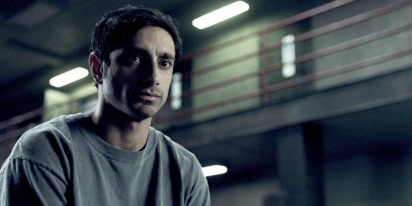 A man sits in a prison open area and looks ahead in The Night Of.