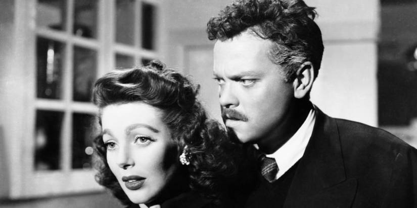 Orson Welles standing behind Loretta Young in The Stranger