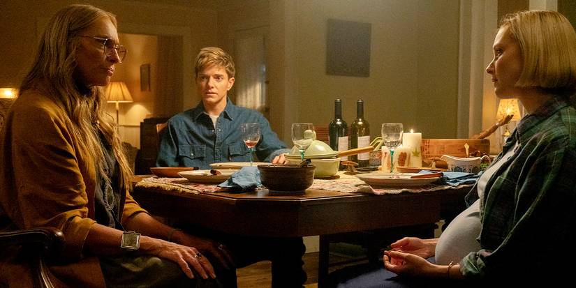 Toni Collette faces Sarah Gadon as Mae Martin looks on around a dinner table in Wayward.