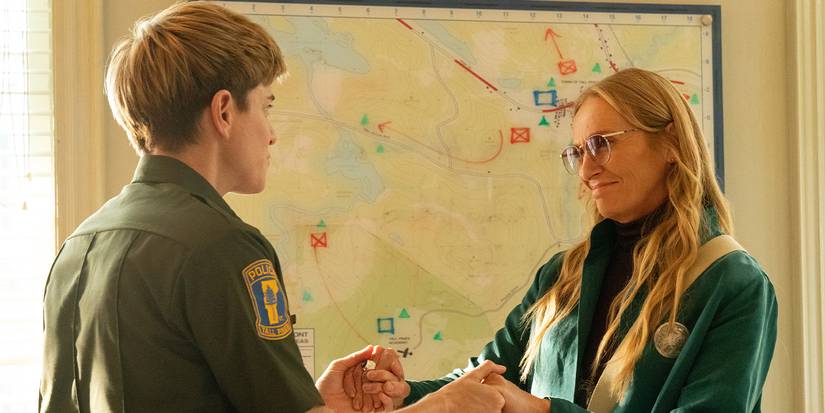 Mae Martin in a police uniform and Toni Collette clasping hands and talking in an office in Wayward.