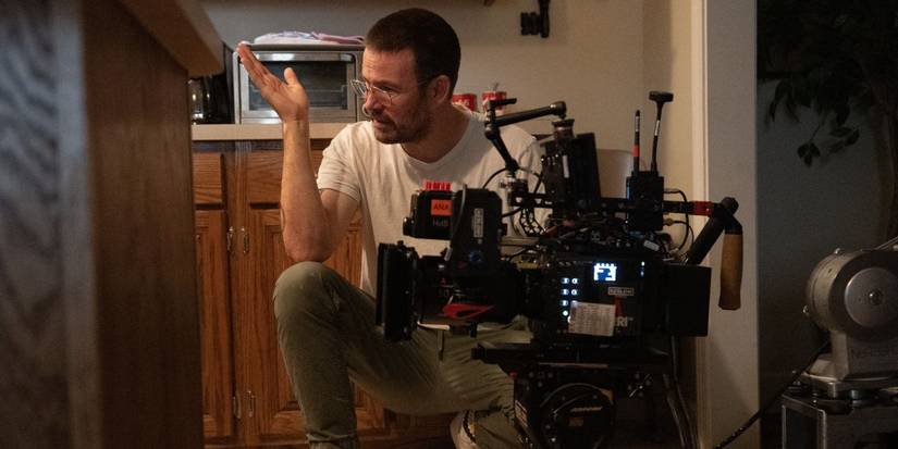 Zach Cregger crouching down next to a camera on the set of Weapons.