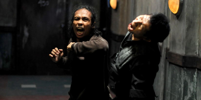 A man hits another man in a dark corridor