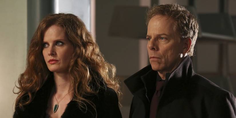 Zelena and Hades stand next to each other with serious expressions on their faces in Once Upon a Time.