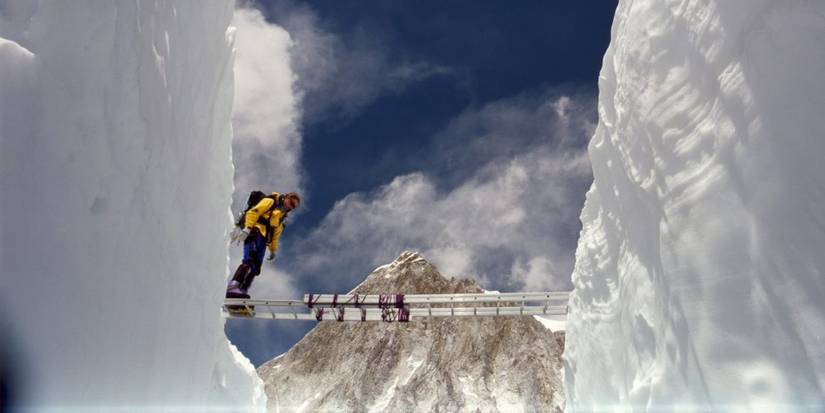 A climber traversing a ladder between two ice walls on Mount Everest in Everest