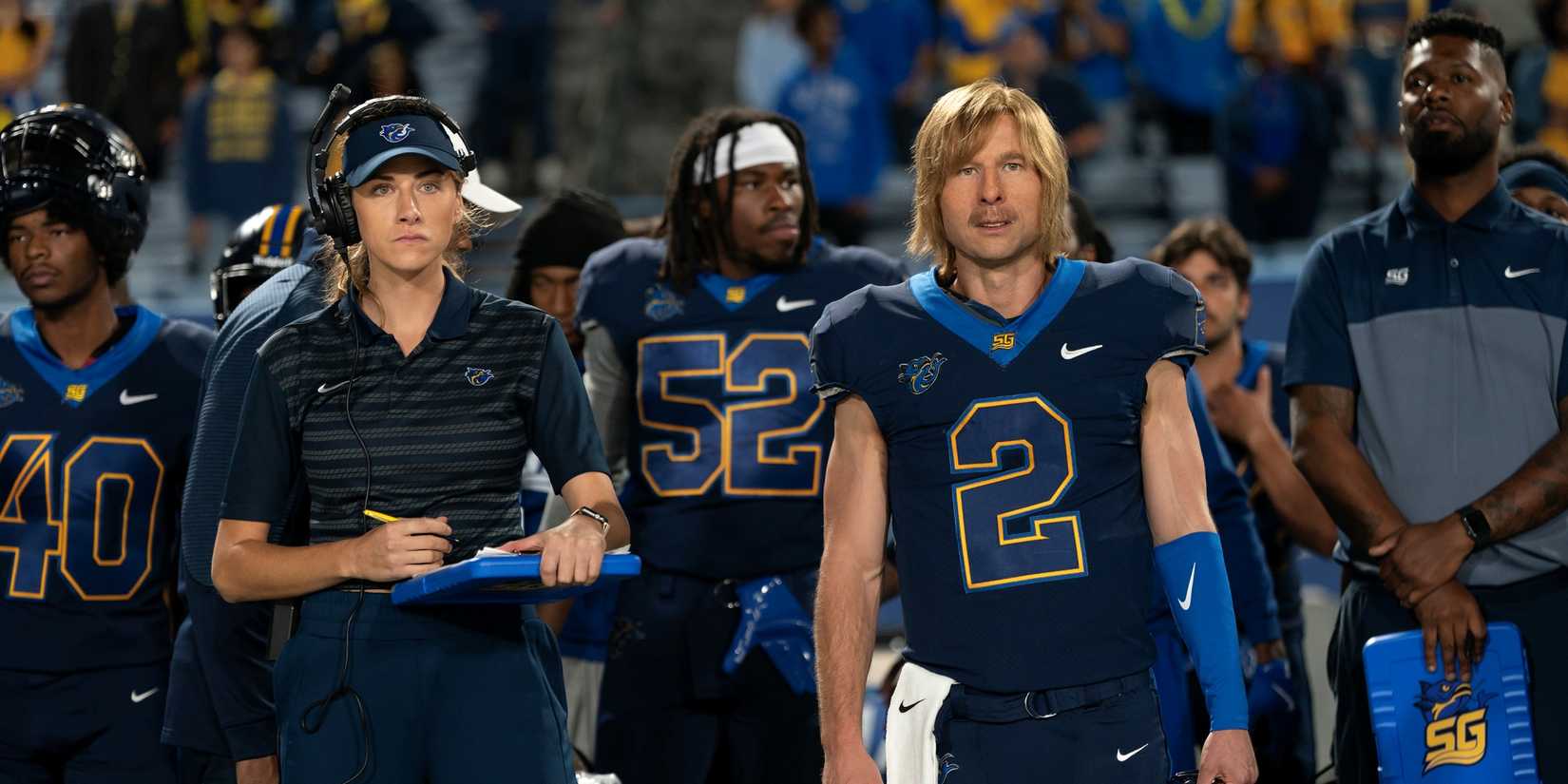 Perry Mattfeld as Ricky Hudson standing next to Glen Powell as Chad Powers in uniform in Chad Powers