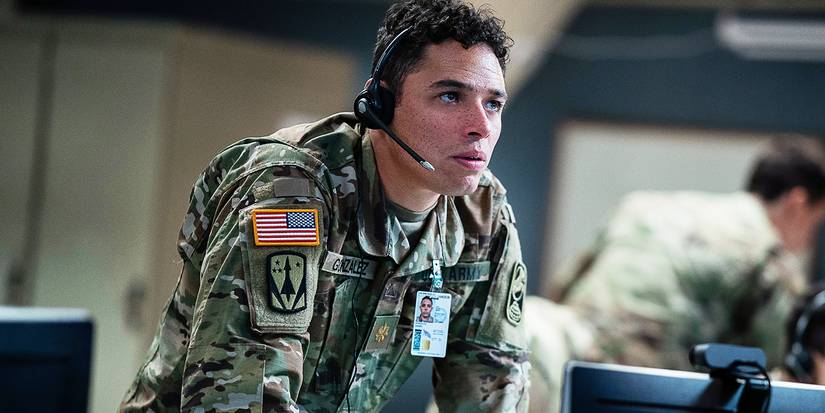 Major Daniel Gonzalez leaning on a table in a control room with a headset on, looking up in concern.