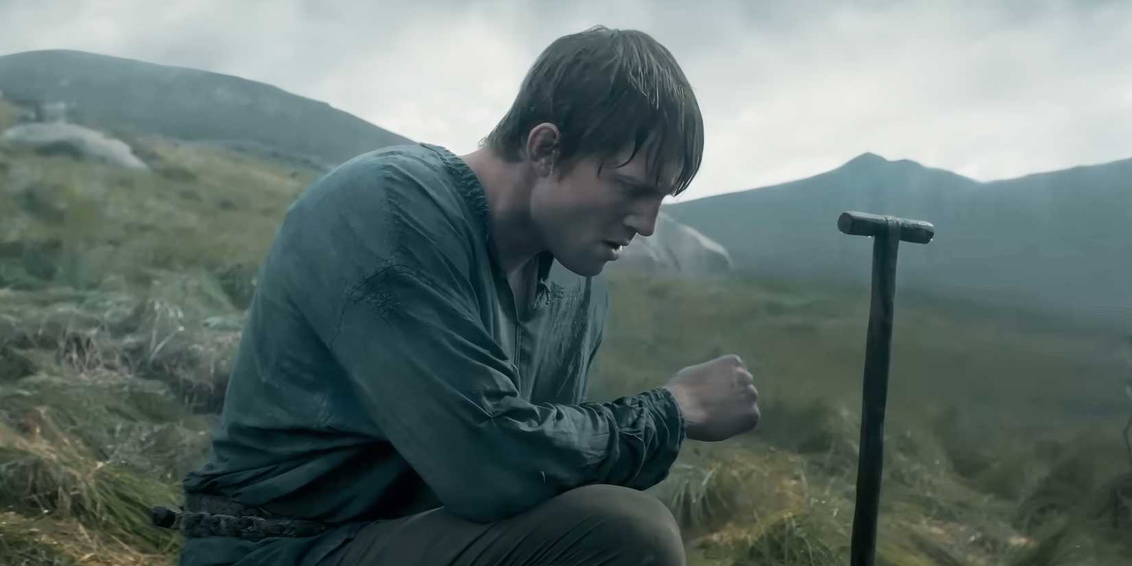 Dunk kneeling in the rain in a field at someone's grave.