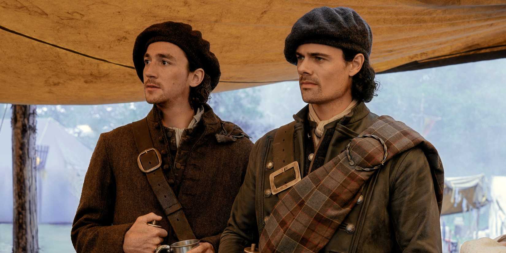 Jamie Roy as Brian standing next to Rory Alexander as Murtagh under a tent in Outlander: Blood of My Blood.