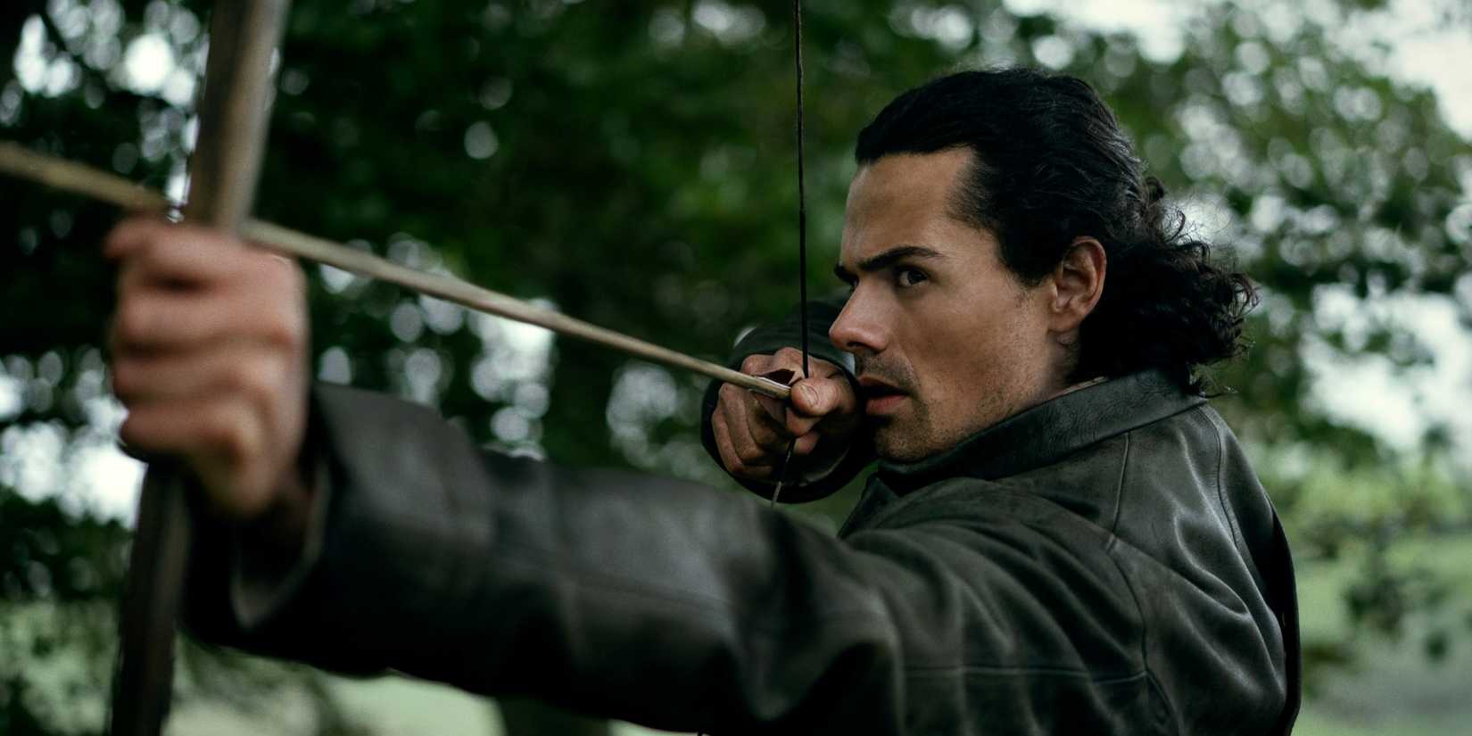 Jamie Roy as Brian Fraser shooting an arrow with a bow in Outlander: Blood of My Blood