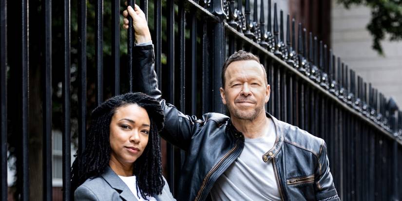 Sonequa Martin-Green as Lena leaning on an iron gate with Donnie Wahlberg as Danny in Boston Blue