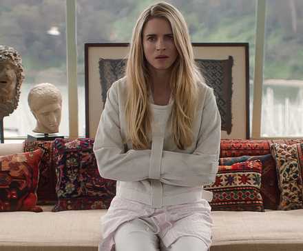 Brit Marling in a straitjacket sits on a couch in a house in The OA.