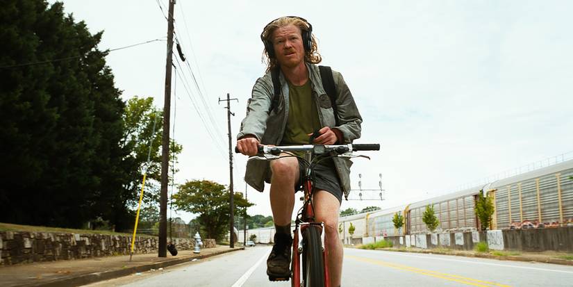 Teddy (Jesse Plemons) riding his bike with headphones on in Bugonia