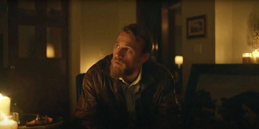 Charlie Hunnam sitting down and looking up at someone to his right in Jungleland.