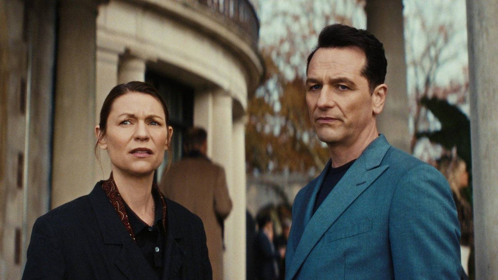 Claire Danes as Aggie and Matthew Rhys as Nile outside a stone building looking perplexed in The Beast in Me.