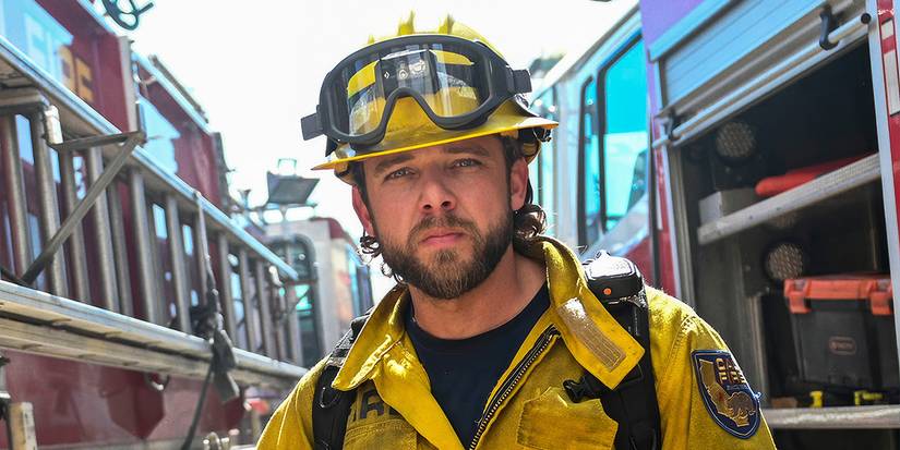 Max Thieriot as Bode Leone standing in between two fire trucks in his fire gear in Fire Country Season 4