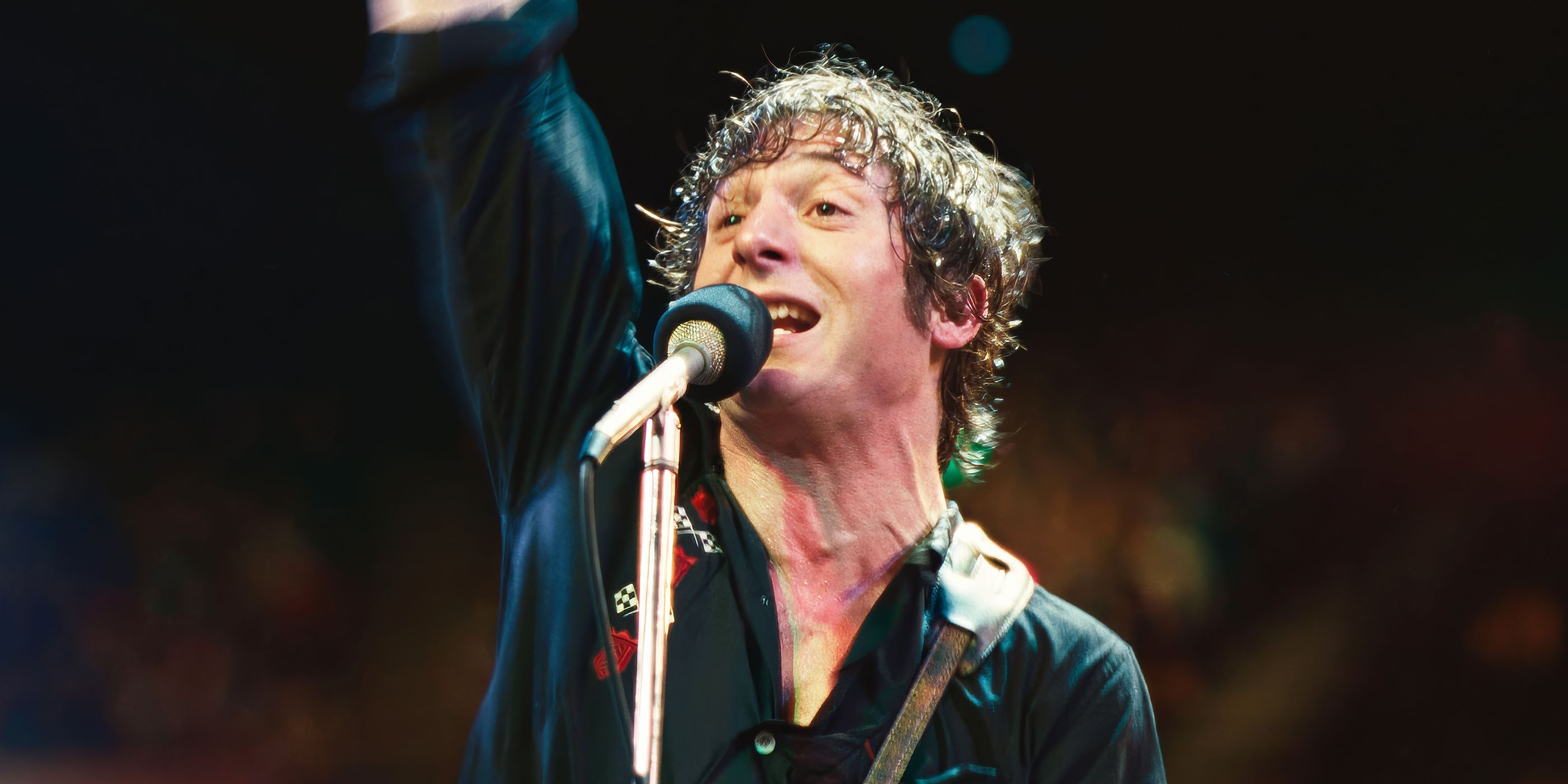 Custom image of Bruce Springsteen (Jeremy Allen White) performing on stage at a mic with his arm raised.