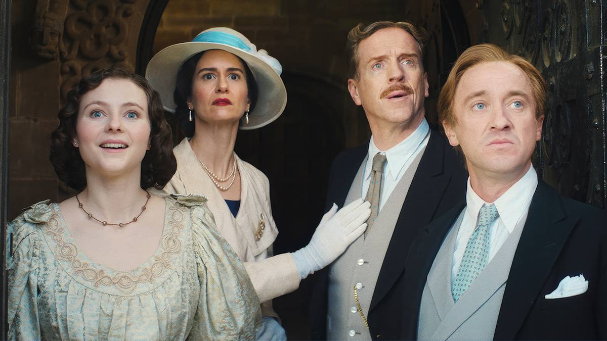 Thomasin McKenzie, Katherine Waterston, Damian Lewis and Tom Felton look at something outside their manor in 'Fackham Hall' image