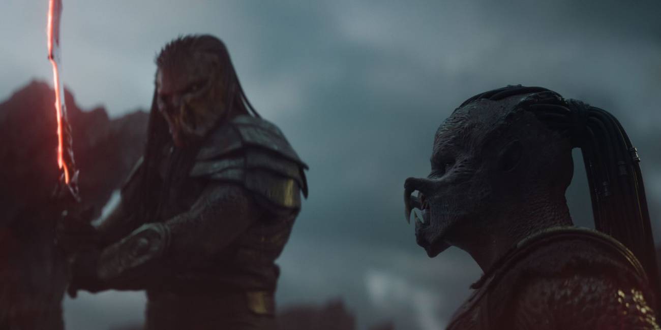 A large Predator holding a sword over a smaller Predator in Predator: Badlands.