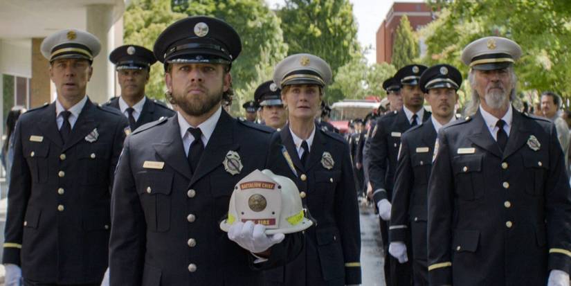 Max Thieriot as Bode Leone walking in a funeral procession with his father's fire helmet in Fire Country