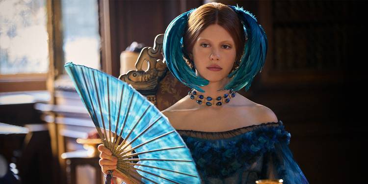 Elizabeth in a blue dress with blue feathers in her hair, holding a blue fan.