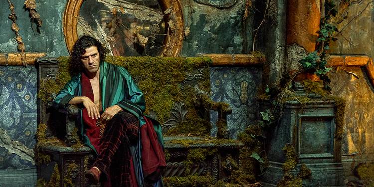 Victor Frankenstein scowls on a bench overgrown with moss in an open silk robe and velvet pants.