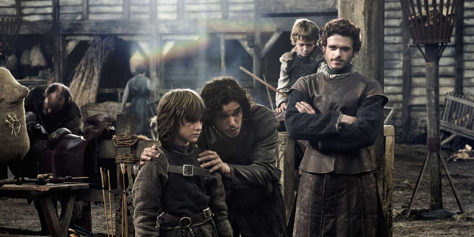 A man talks to a young boy in a town square in the pilot episode of Game of Thrones.