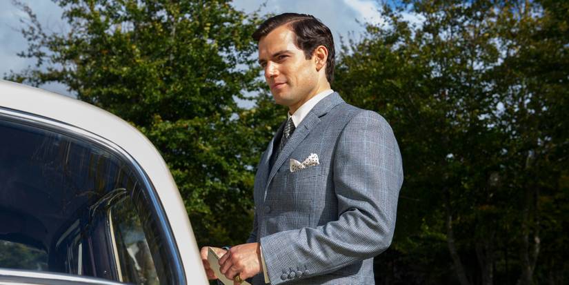 Henry Cavill sebagai Solo tersenyum di dekat mobil yang diparkir di The Man from UNCLE