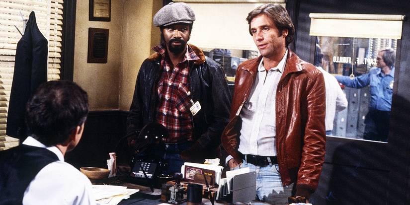 Michael Warren's Robert and Daniel J. Travanti's Frank standing in front of a desk in Hill Street Blues