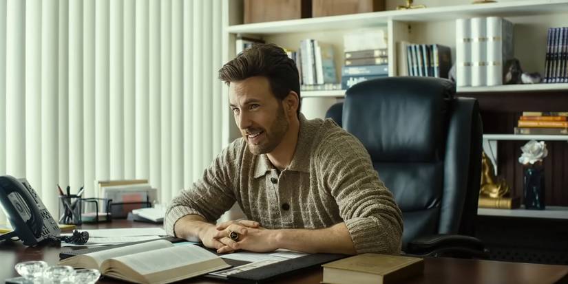 Chris Evans as Reverend Drew Devlin sitting at a cluttered office desk in Honey Don't!