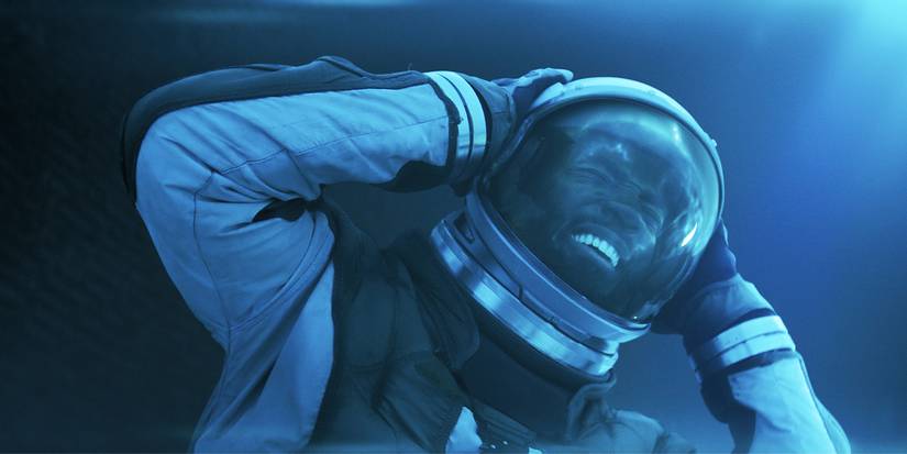 Trevante grips his head with an expression of agony in a space suit in Invasion Season 3.