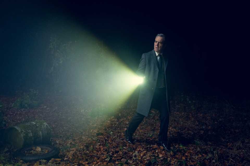 James Nesbitt shining a flashlight in a dark woodland in Run Away